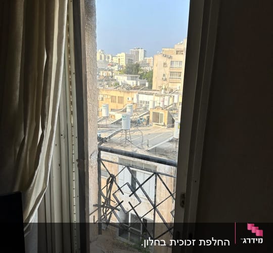 חלון זכוכית עם סורגים וברקע נוף עירוני